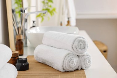 Rolled soft towels on white table in bathroom
