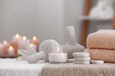 Spa composition with burning candle and herbal bags on massage table in wellness center