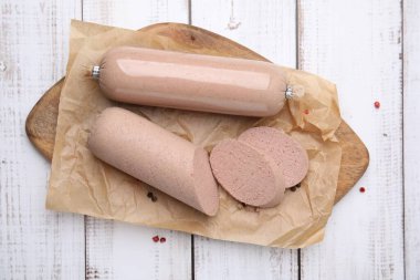 Board with delicious liver sausage on white wooden table, top view