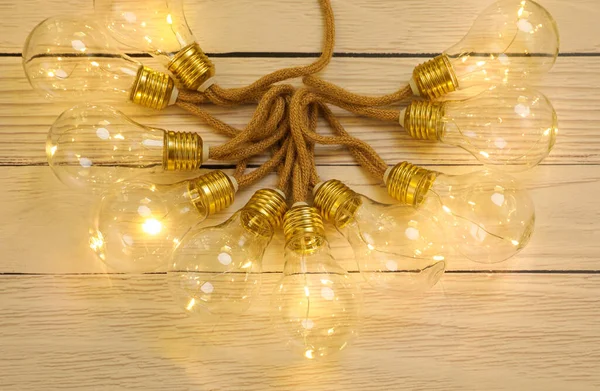 String lights with lamp bulbs on wooden background, top view