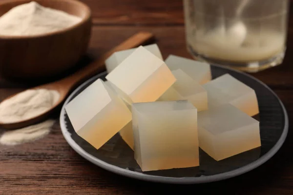 Agar-agar jelly cubes on wooden table, closeup