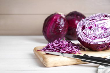 Cut fresh red cabbage with knife on white wooden table. Space for text