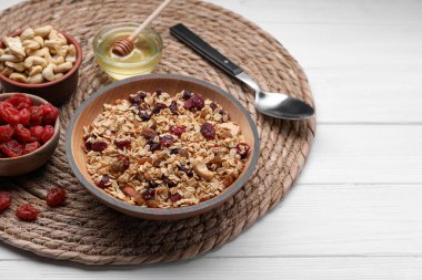 Tasty granola served with nuts and dry fruits on white wooden table. Space for text