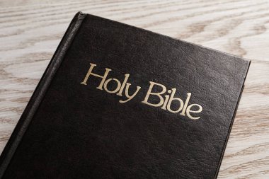 Bible with dark cover on wooden table, closeup. Christian religious book