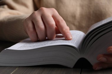 Ahşap masada İncil okuyan kadın, yakın plan.