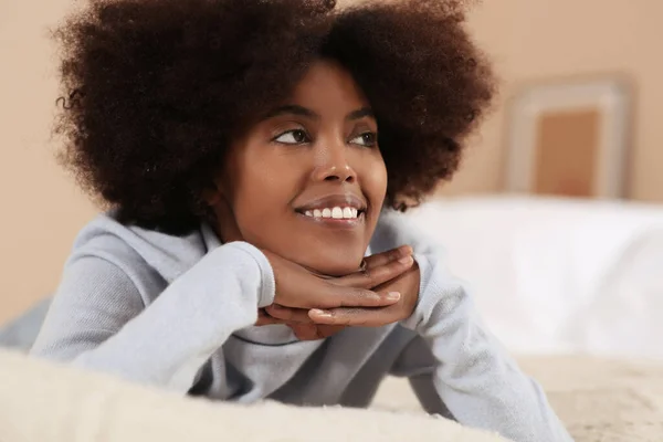 Smiling African American woman on bed at home
