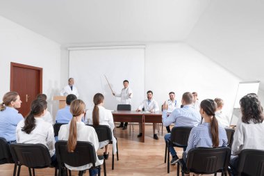 Doctors giving lecture near projection screen in conference room