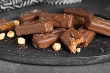 Delicious chocolate candy bars with caramel and nuts on grey table, closeup