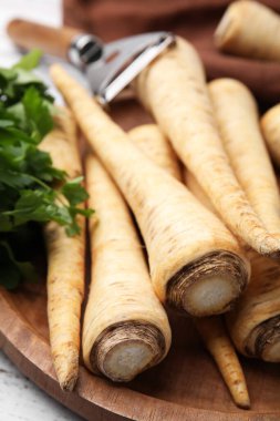 Raw parsley roots and fresh herb on wooden board, closeup