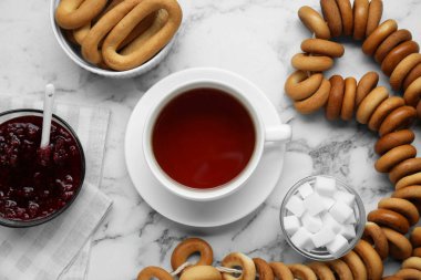 Flat lay composition with delicious ring shaped Sushki (dry bagels) and cup of tea on white marble table