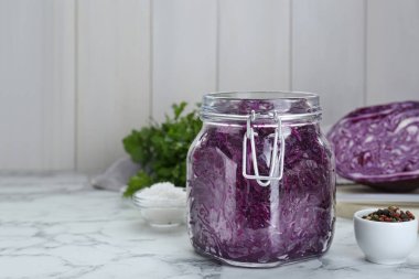 Tasty red cabbage sauerkraut and ingredients on white marble table. Space for text