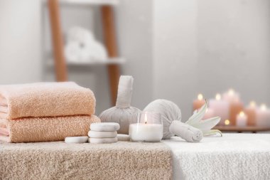 Spa composition with burning candle and herbal bags on massage table in wellness center