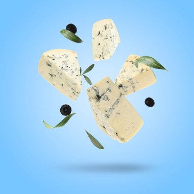 Pieces of delicious cheese, olives and leaves falling on light blue background