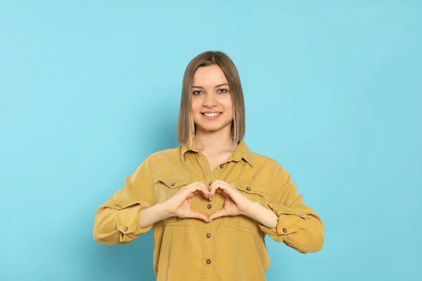 Young Woman Making Heart Hands Turquoise Background Volunteer Concept — Stockfoto