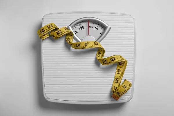 Weight loss concept. Scales and measuring tape on white background, top view