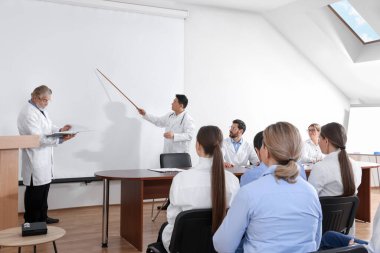 Doctors giving lecture near projection screen in conference room