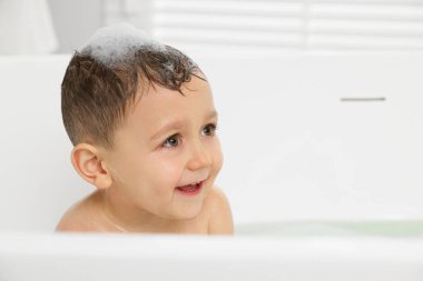 Cute little boy washing hair with shampoo in bathroom. Space for text