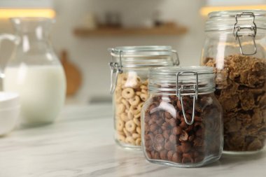 Mutfaktaki beyaz mermer masada farklı kahvaltı gevrekleri olan cam kaplar. Metin için boşluk