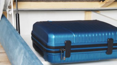 Yatağın altındaki çekmecede mavi bavul var.