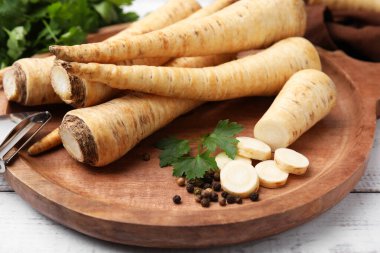 Raw parsley roots and fresh herb on wooden board, closeup