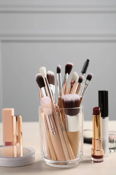 Set of professional brushes and makeup products on wooden table indoors