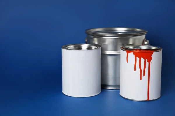 Cans of orange paint on blue background. Space for text