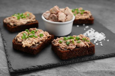 Tasty sandwiches with cod liver, salt and green onion on light grey table