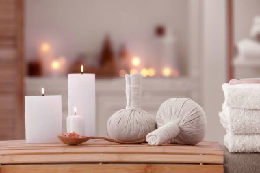 Spa composition with burning candles and herbal bags on massage table in wellness center
