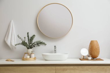 Stylish mirror, eucalyptus branches and vessel sink in modern bathroom. Interior design