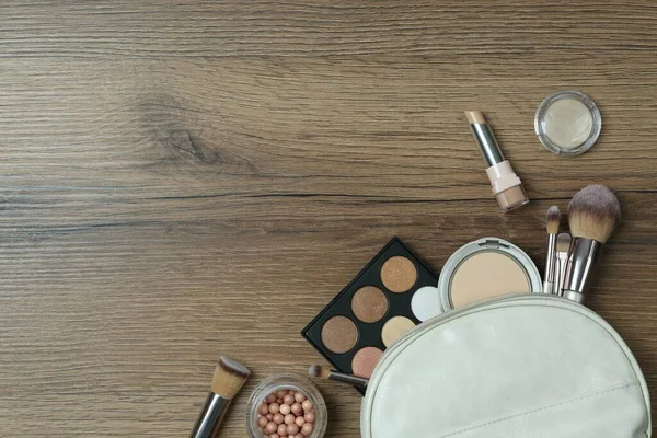 Flat lay composition with makeup products on wooden table, space for text