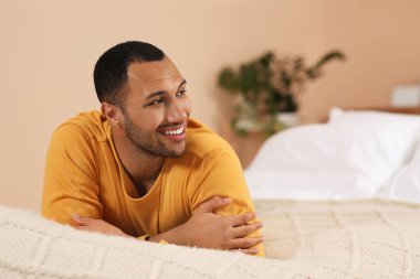 Portrait of smiling African American man on bed at home. Space for text