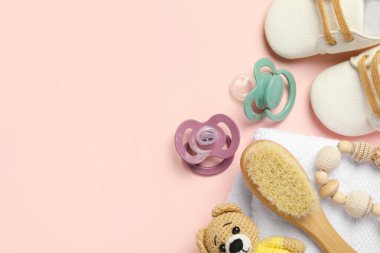 Düz kompozisyon, emzikler ve pembe arka planda diğer bebek eşyaları. Metin için boşluk