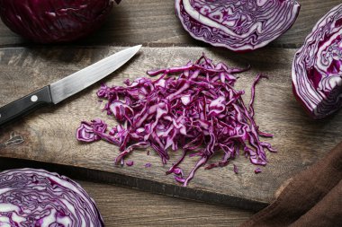 Delicious fresh shredded red cabbage and knife on wooden table