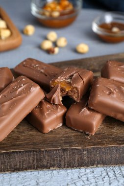 Delicious chocolate candy bars with caramel and nuts on grey wooden table