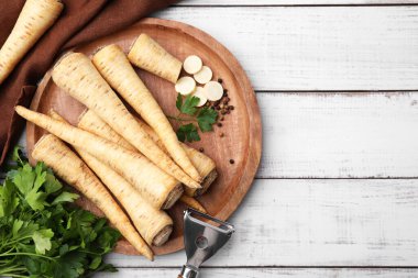Raw parsley roots and bunch of fresh herb on white wooden table, flat lay. Space for text