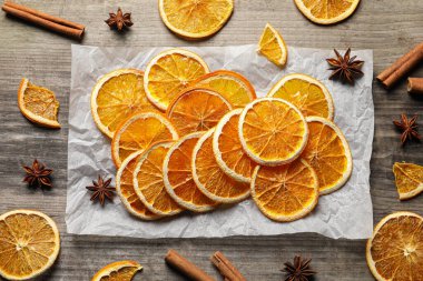 Many dry orange slices and spices on wooden table, flat lay