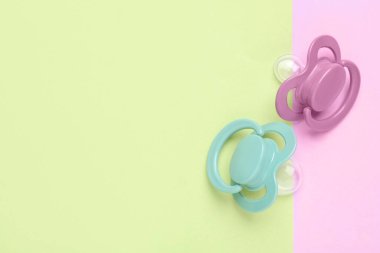 Baby pacifiers on color background, top view. Space for text