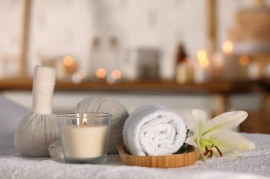Spa composition with burning candle and herbal bags on massage table in wellness center