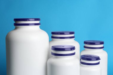 White medical bottles on light blue background, closeup