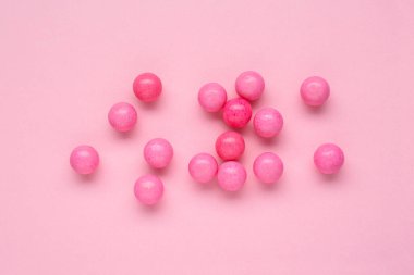 Many bright chewy gumballs on pink background, flat lay