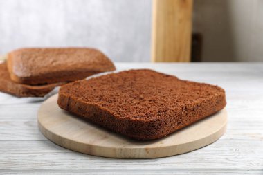 Layers of homemade chocolate sponge cake on white wooden table