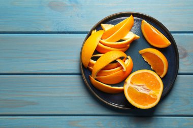Orange peels preparing for drying and fresh fruit on light blue wooden table, top view. Space for text