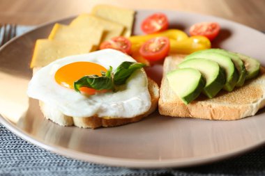 Tasty toasts with fried egg, avocado, cheese and vegetables on table, closeup
