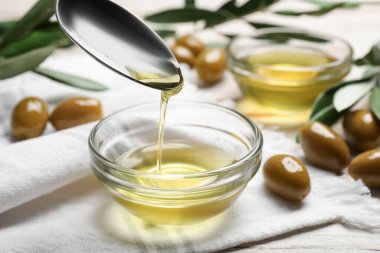 Kase üzerinde pişirme yağı ve beyaz ahşap masada zeytin, yakın çekim
