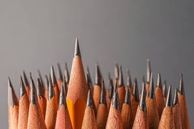 Many sharp graphite pencils on grey background, closeup. Space for text