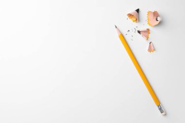 Graphite pencil and shavings on white background, flat lay. Space for text