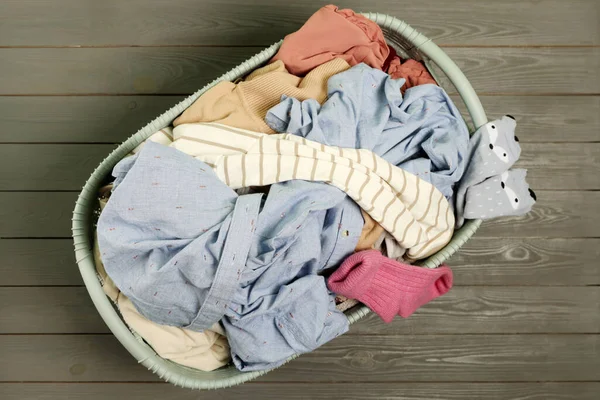 Laundry basket with clothes on dark grey wooden floor, top view