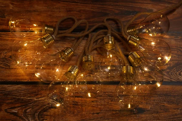 String lights with lamp bulbs on wooden table, top view