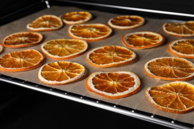 Dry orange slices on parchment paper, closeup