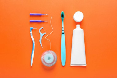 Flat lay composition with dental floss and different teeth care products on orange background